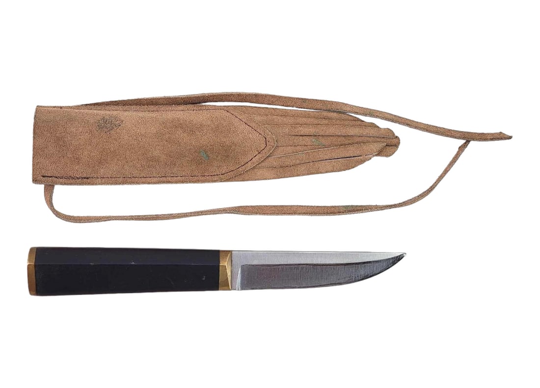 Hackman Finland Tapio Wirkkala Puukko Knife w/Sheath: A fixed straight back stainless steel blade with hidden tang. A brass bolster and butt surround a nylon handle. In like-new condition and housed in a tasseled leather belt sheath. Sheath shows signs o