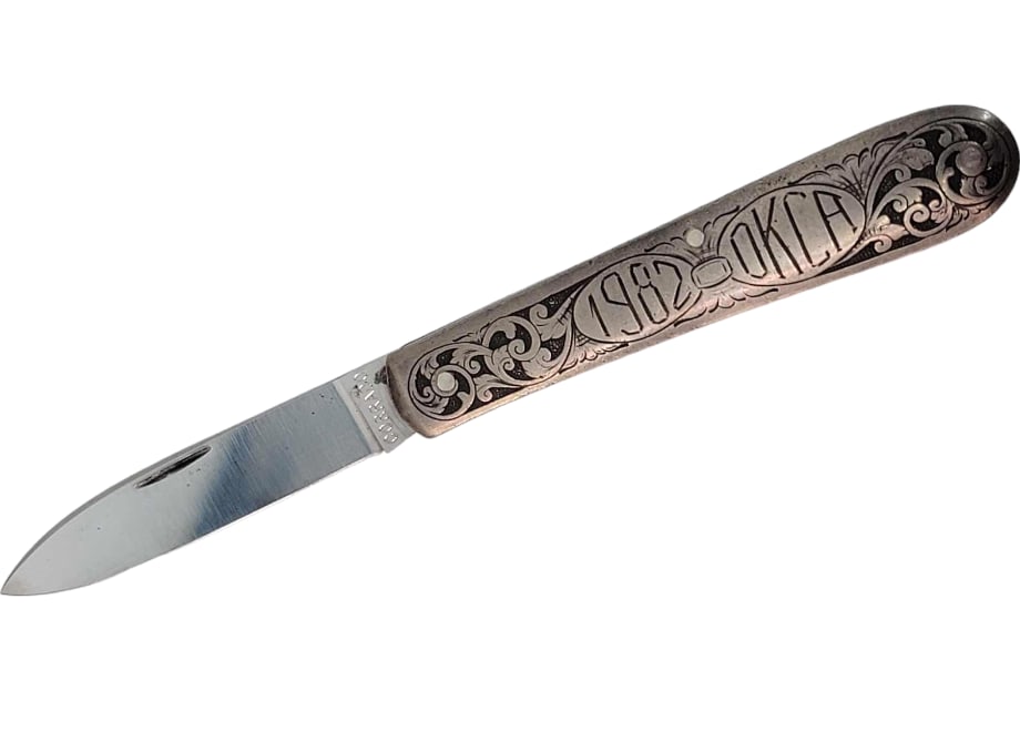 1982 OKCA Commemorative Jim Corrado Folding Pocket Knife: A beautiful and highly detailed swayback leaf shape folding pocket knife by Knifemakers Guild member Jim Corrado. Its handle has three pins and ornately scrolling details along with the etching ‘198