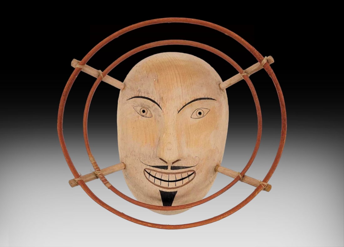 Yup'ik Shaman Spirit Mask: A minimalist polychromatic Yup'ik shaman spirit mask handcrafted from wood with double bentwood frame and sinew ties. A string loop is affix en verso for hanging; piece demonstrates some light sta