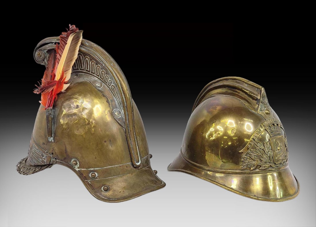 Antique Brass French Firefighter Helmets c.1900: Two antique brass Sapeurs Pompiers, or firefighter's helmets, with French origin circa late 19th to early 20th Century. The larger features a high comb, open link chin strap, and ornate plate with