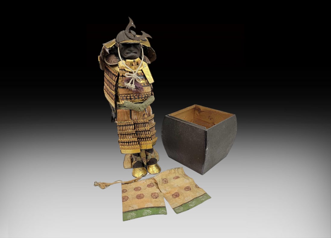 Japanese Samurai Armor Yoroi w/ Wooden Box: A Japanese Samurai armor yoroi featuring a kabuto (helmet), d? or domaru (cuirass or chestplate), kusazuri (multipart skirt pendant), sode (shoulder guards), and more. Pieces may be assembled for disp