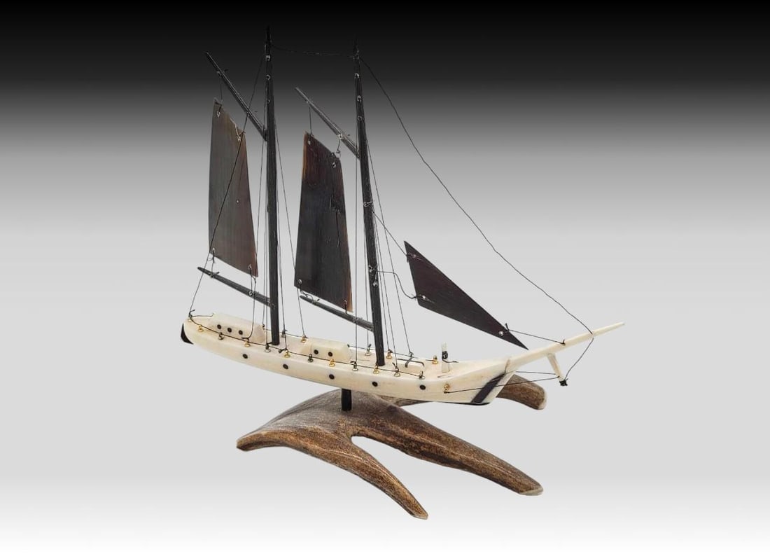 Walrus Tusk, Baleen & Antler Schooner - Al Kaloke: A two-masted schooner with walrus tusk hull topped with baleen masts, rigging, and sails. The hull is accented with metal cleats and sits upon a three-tined section of antler by way of a baleen rod. T