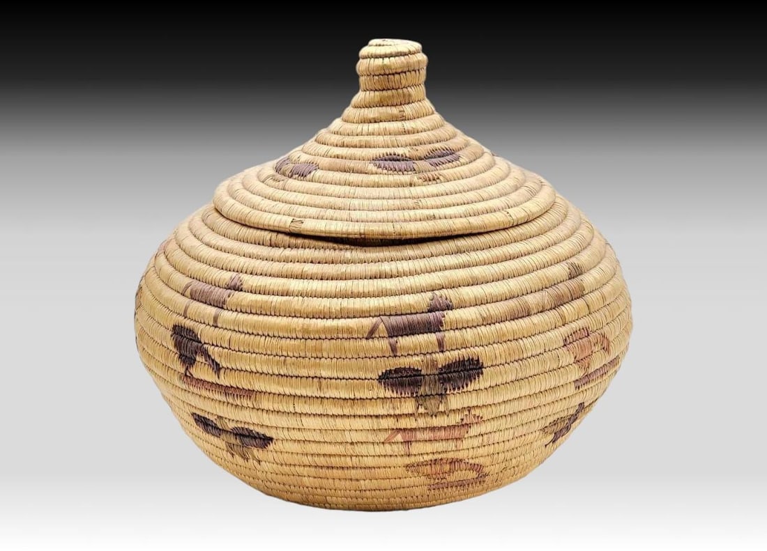 12" Yup'ik Coiled Grass Basket w/ Animal Embroidery & Lid: A large Yup'ik coiled grass lidded basket with embroidered polychrome animals including wolves, ravens, salmon, and butterflies. Underside features bright pink and purple woven accents, the lid a 