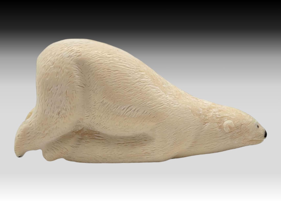 Walrus Tusk Sliding Polar Bear - Alvin Aningayou: A walrus tusk carved and incised polar bear with inset baleen eyes, posed in a position to be sliding down an icy glacier into the Arctic water. Signed on the underside by Yup'ik artist Alvin Anin