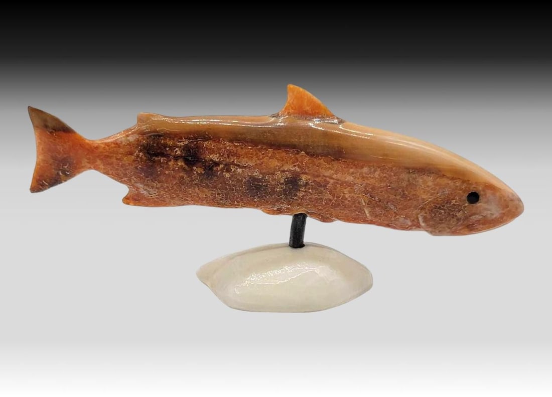 Fossilized Walrus Tusk Salmon w/ Baleen - Joseph K. Slwooko: A richly colored fossilized walrus tusk salmon, mounted upon a sample of contemporary walrus tusk via a baleen rod. Initialed on the underside of the base for Yup'ik artist Joseph K. Slwooko (1952