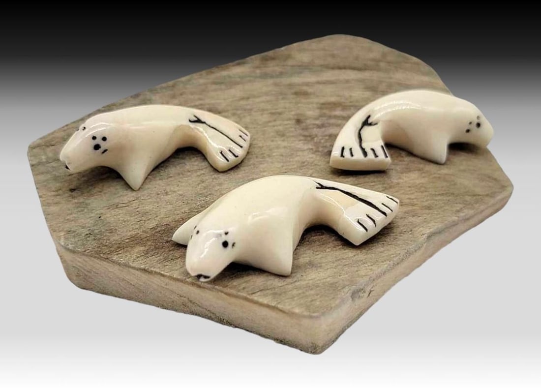 Walrus Tusk & Scrimshaw Seals on Fossilized Walrus Tusk Base - Muktoyuk: A bob of three seals, all carved from walrus tusk, accented with scrimshaw details, and mounted upon an irregularly shaped slice of fossilized tusk. Signed on the edge by a member of the Iñupiaq fami