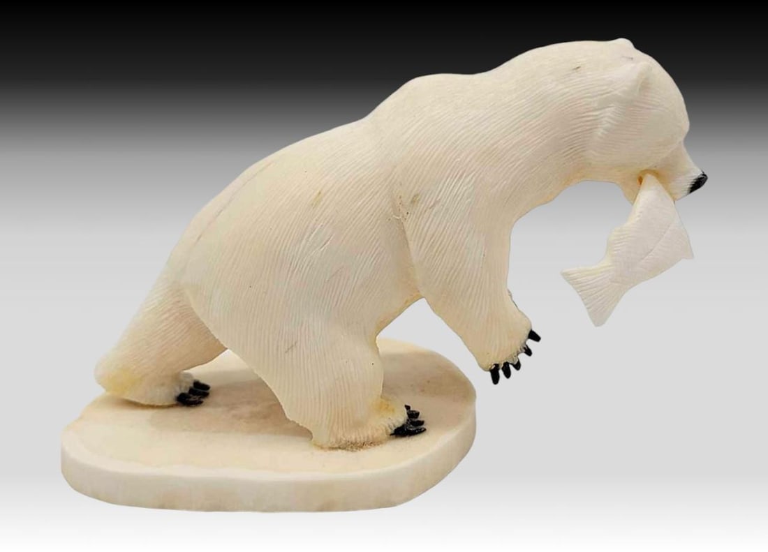 Walrus Tusk & Baleen Polar Bear w/ Salmon - Aningayou: A walrus tusk carved and incised polar bear figurine with inset baleen claws and a tusk salmon within its mouth. Mounted upon a slice of walrus tusk, and signed on the underside by a member of the pro
