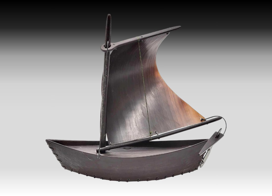 Single Mast Baleen Sailboat - Allen Kuhikoon: A single mast sailboat with a dark baleen hull and rudder, topped with a baleen mast and a richly shaded baleen sail. Signed on the underside by Yup'ik artist Allen Kuhikoon of Gambell, Alaska. Me