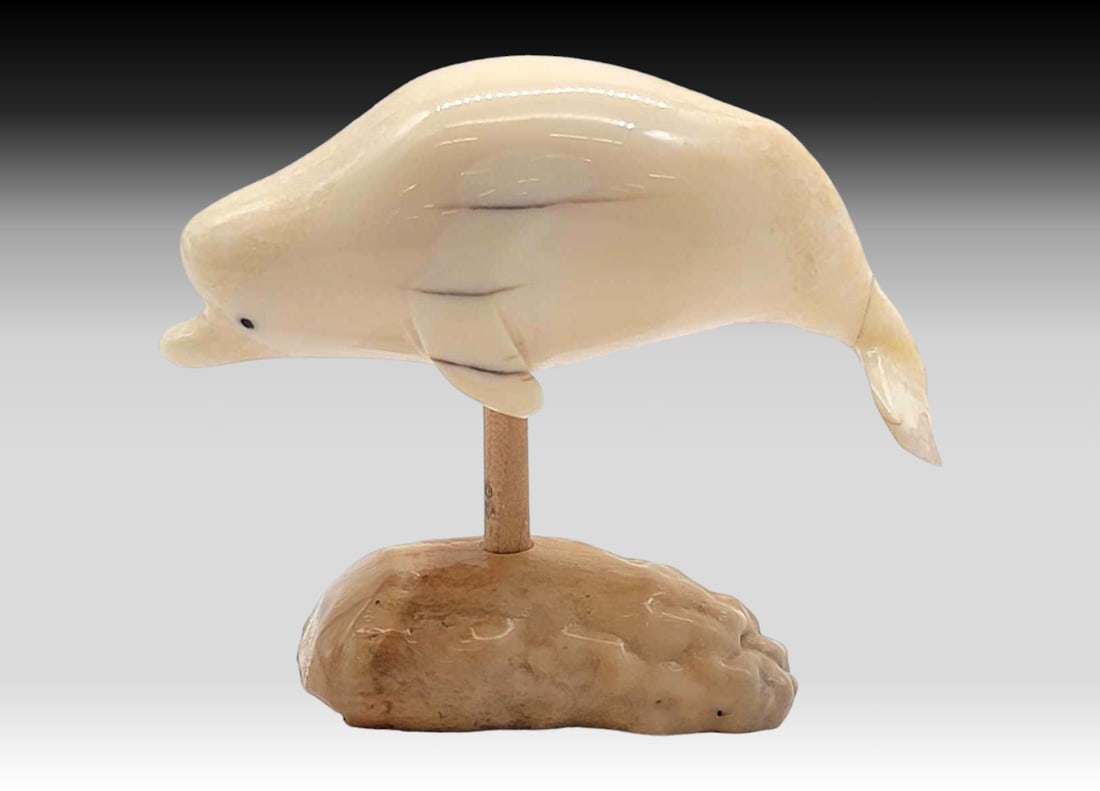 Walrus Tusk Beluga Whale Figurine on Fossilize Walrus Tusk Base: A beluga whale, carved from walrus tusk with inset baleen eyes; mounted upon a removable rod upon a section of fossilized walrus tusk dentine. Fluke has a crack where it connects to the rest of the wh