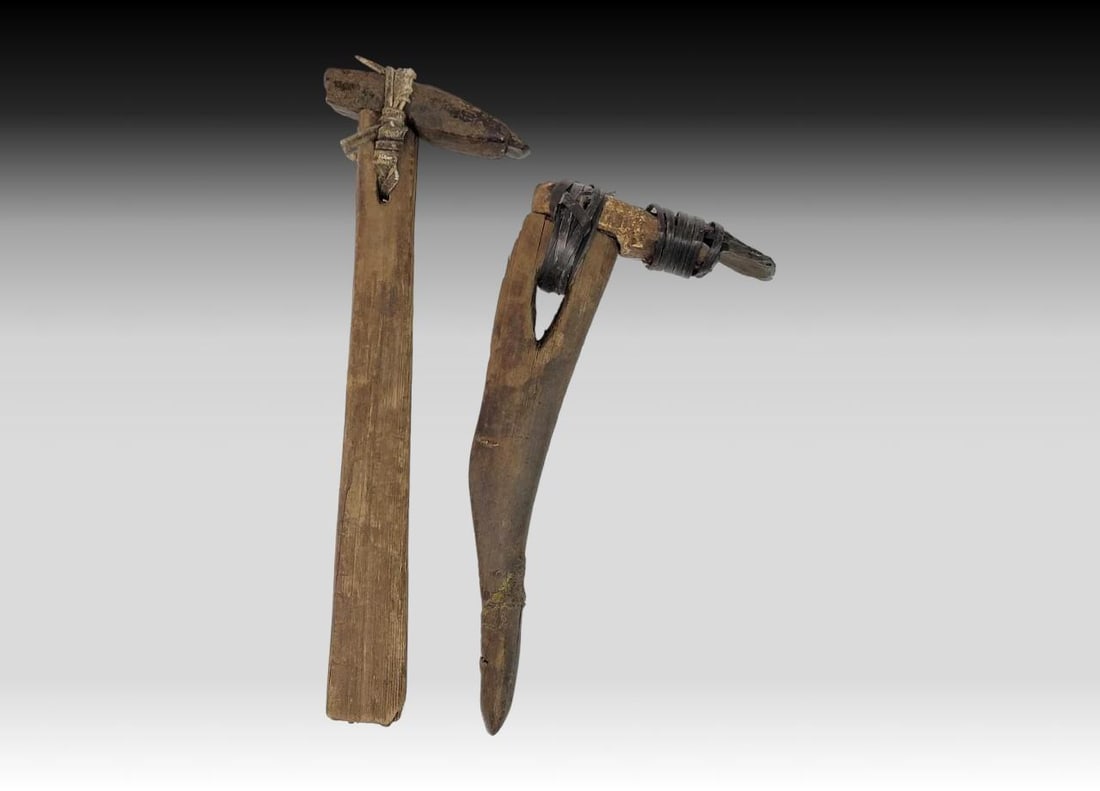 Two Eskimo Adze Artifacts: Two Eskimo adze artifacts, each from the 19th century or earlier. Both handles are fitted with pointed stone heads; one lashed together with sinew, the other baleen. Handles and blades show signs of w