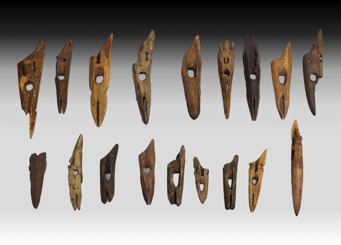 18x Punuk & Thule Toggling Harpoon Heads: Eighteen Punuk or Thule culture fossilized walrus tusk toggle harpoon head artifacts with socket and spur at base, drilled hole above socket for harpoon line, and slot to hold a friction-fitted sharpe