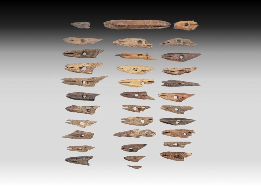 34x Punuk & Thule Toggle Harpoon Heads: Thirty-four fossilized walrus tusk toggle harpoon head artifacts with socket and spur at base, drilled hole above socket for harpoon line, and slot to hold a friction-fitted sharpened stone or bone po