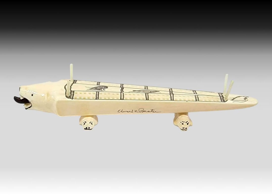 Walrus Tusk Polar Bear Cribbage Board w/ Scrimshaw Seals - Edward N. Penatac: A mid 20th century walrus tusk cribbage board with wide end carved into the face of a mighty polar bear. Top surface features scrimshaw walrus and seals, while the fee consist of a pair of seal pups c