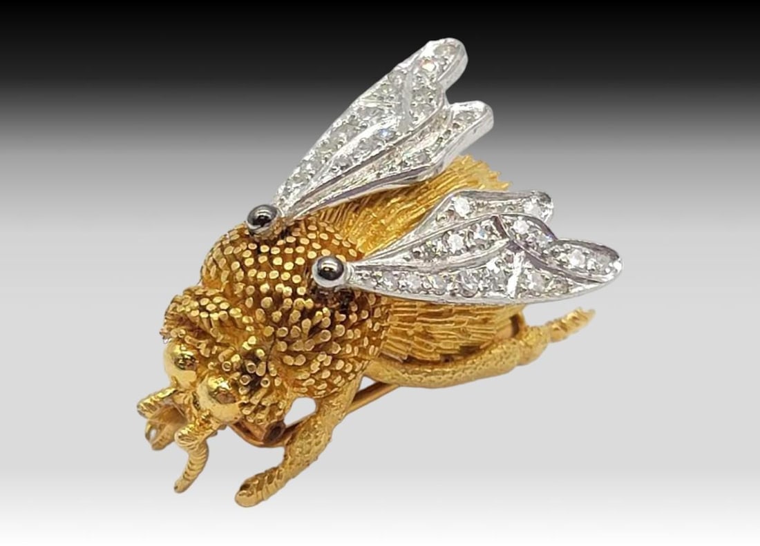 18k Gold & Diamond Tiffany France Bumble Bee Brooch: A bumble bee brooch with an 18 karat yellow gold body and diamond-encrusted 18 karat white gold wings. The selection of round diamonds includes eight at 1.25mm, 4 at 0.5mm, and eighteen at 1mm in diam