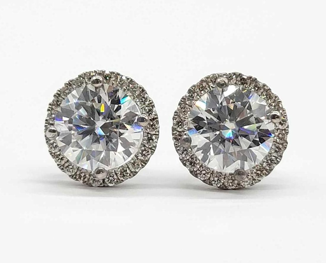6.00 ctw Diamond Moissanite Halo Earrings in 14k White Gold: A magnificent pair of lady's 14 karat white gold diamond and moissanite halo earrings with friction backs, each earring featuring one 3.00 carat round, modified brilliant cut moissanite measuring 