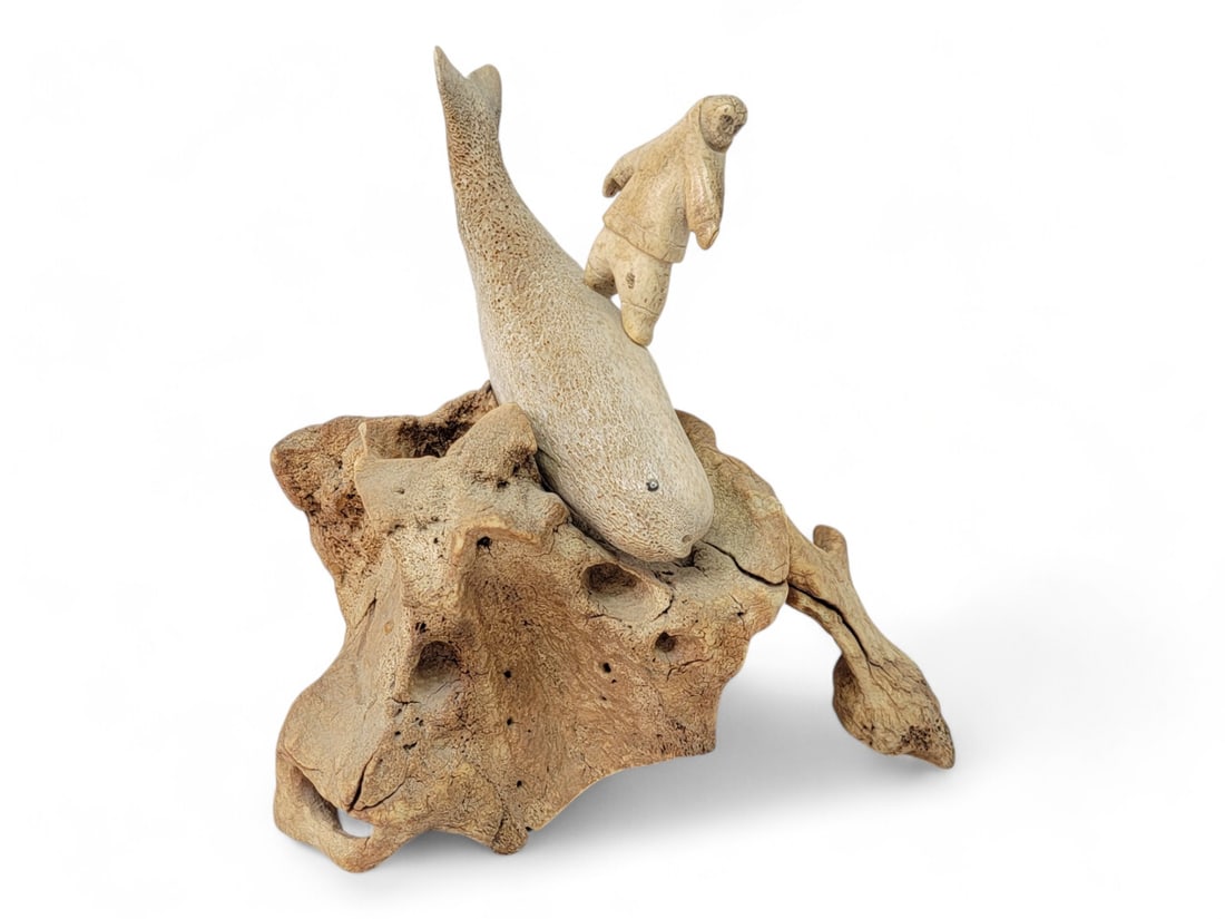 Eskimo Carved Bone Sculpture of Whale Rider: A stunning whalebone sculpture depicting a figure riding on a whale, mounted on a piece of mineralized walrus vertebrae. Measures approximately 9" x 7" x 10" tall.
