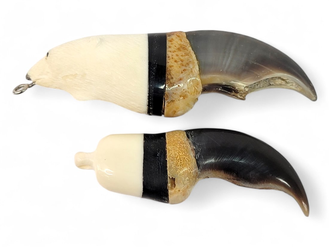 Two Polar Bear Claw Pendants: Two polar bear claws, each capped with a slice of baleen, and further capped with a section of walrus tusk; one tusk piece is carved and incised in the shape of a polar bear. A silver-tone bail has be