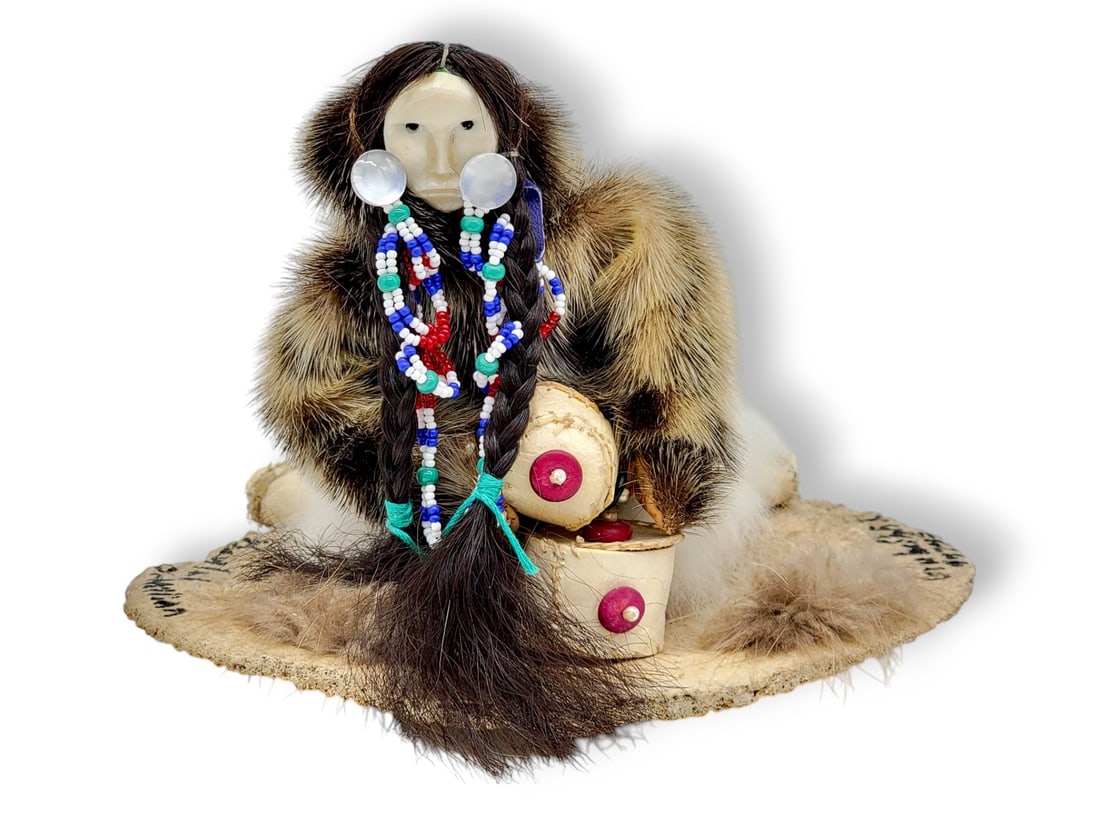 Yup'ik Handmade Story Doll - Beulah Ottillian: A unique handmade doll by Yup'ik doll maker Beulah Ottillian playing a drum dressed in furs with a carved walrus tusk mask, sinew ties, seed bead details mounted on a slice of bone and signed by the m