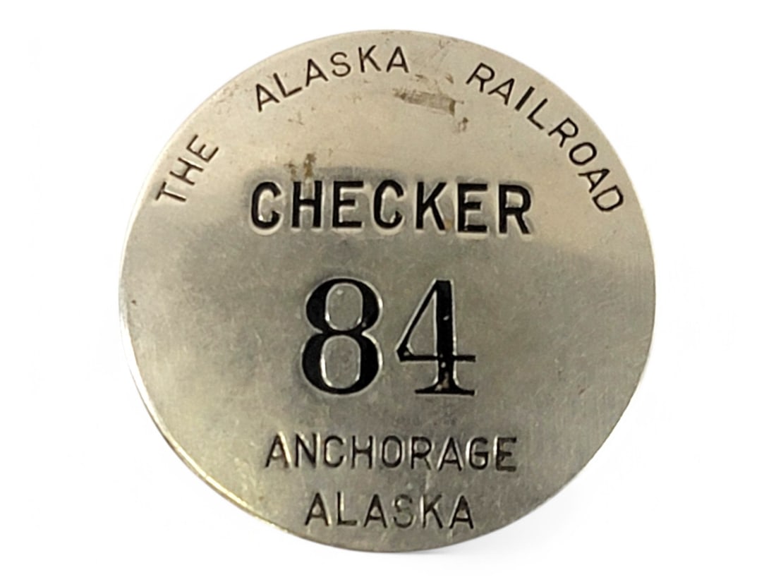 Antique Alaska Railroad "Checker 84" Uniform Badge: An early 20th century Alaska Railroad lapel pin, possibly a mail handler's or ticket taker's uniform badge. It has debossed lettering in black enamel reading Checker 84 Anchorage, Alaska. There are a 