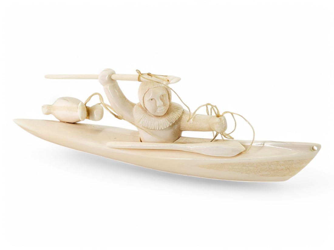 Walrus Tusk Hunter in Kayak - Merle "Wowita" Apassingok: A walrus tusk hunter figuring, positioned within his kayak, harpoon in his right hand, paddle by his side, and seal float to his rear. Signed on the underside by contemporary Yup'ik artist Merle "Wowi
