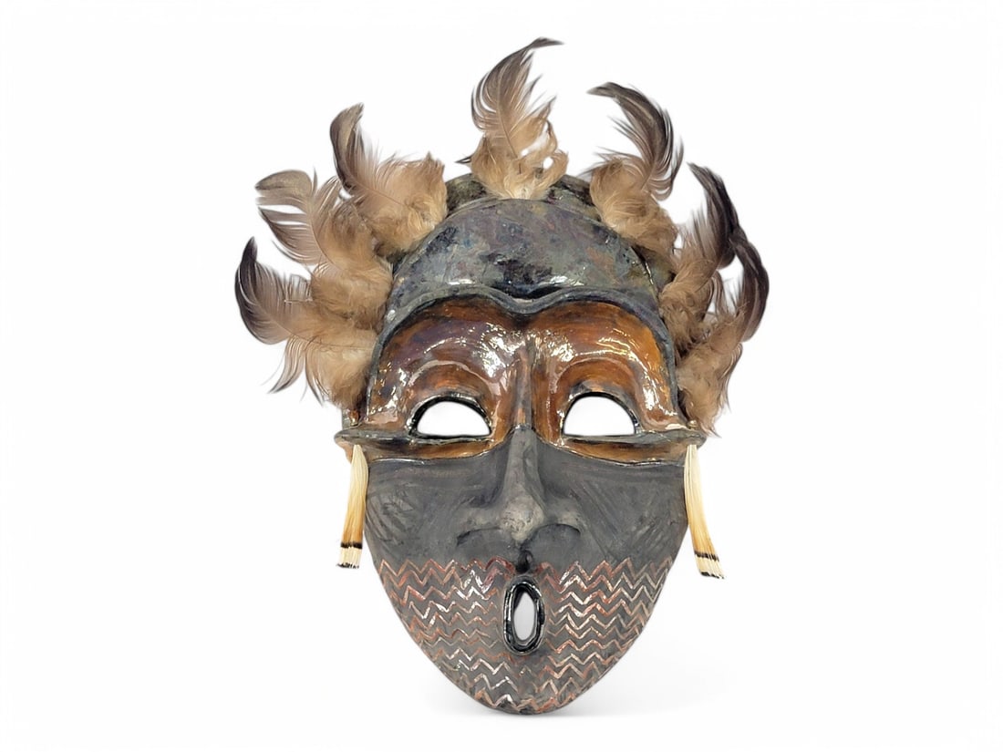 Raku Pottery Mask - Lillian Pitt: A raku pottery mask with painted accents, open mouth, wide eyes, animal fur earrings, and seven feathers upon the head. Signed en verso by Pacific Northwest Native American artist Lillian Pitt (b.1943