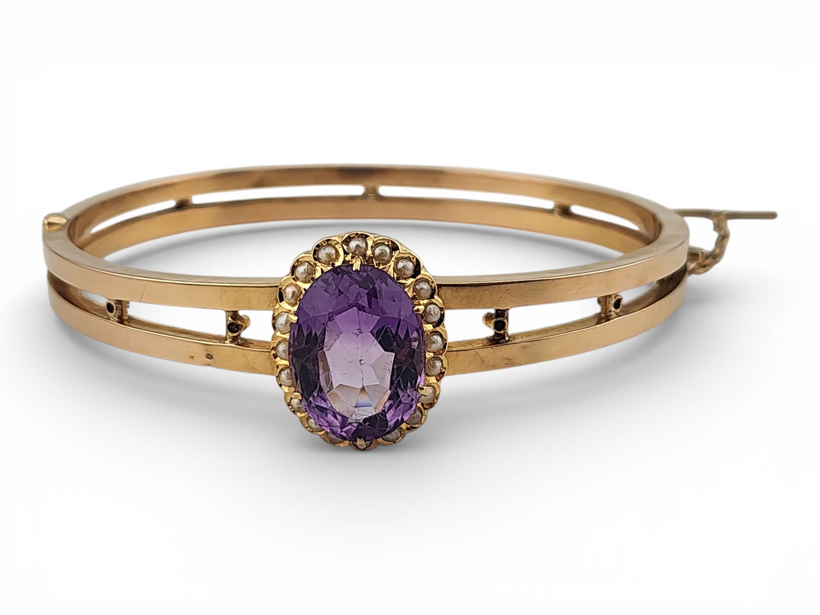 Antique 18k Yellow Gold Amethyst & Seed Pearl Hinged Bangle Bracelet: An antique Victorian, turn-of-the-century, high-purity yellow gold hinged bangle bracelet featuring a central prong-set oval 12.25mm x 16mm faceted amethyst, encircled by twenty 1.5mm seed pearls.