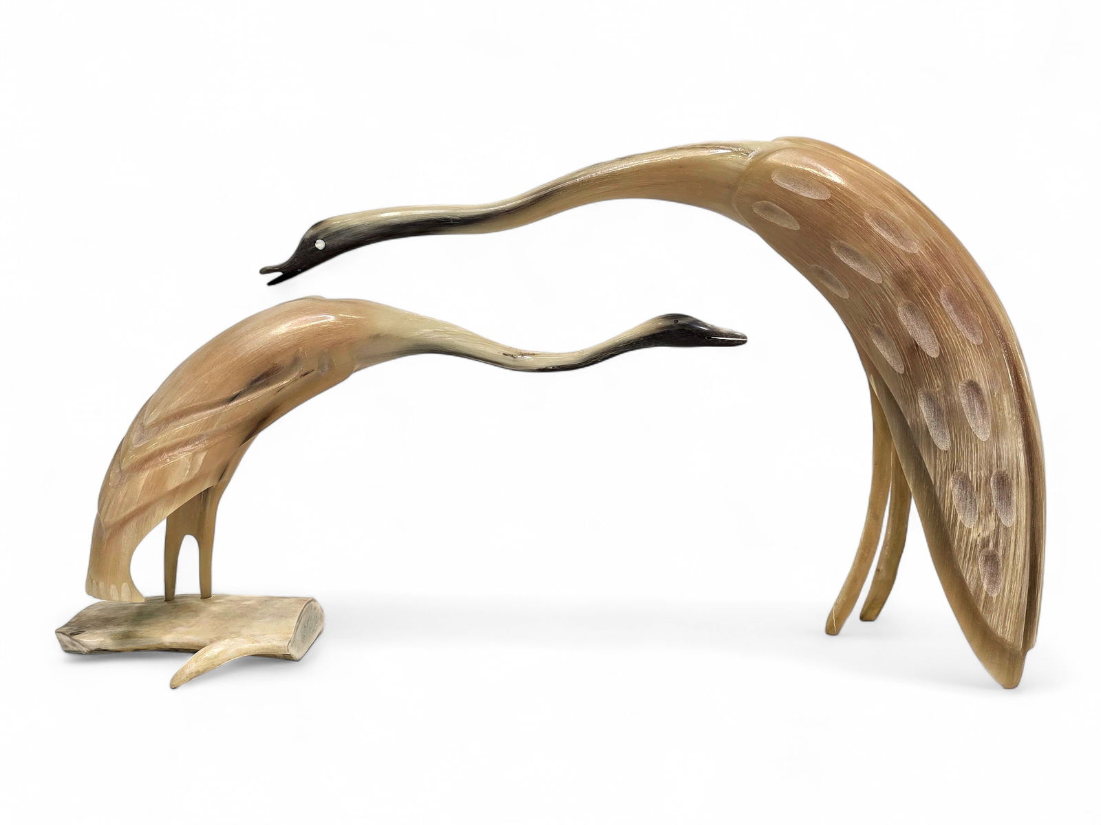 Inuit Musk Ox Horn Cranes - Buddy "Nutik" Alikamik: Two cranes, each carved from musk ox horn; the larger example has inlaid eyes while the smaller example is mounted upon a section of deer antler and signed by Ulukhaktok artist Buddy "Nutik" Alikamik