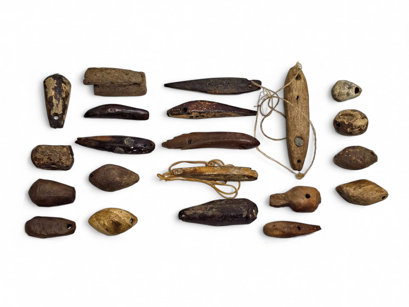 Alaska Native Artifacts - Fishing Lures & Weights: Twenty-one fossilized artifacts crafted from walrus tusk and bone include net weights, spear and harpoon points, float plugs, fishing lures, and more, as shown in the photographs. Largest specimen mea