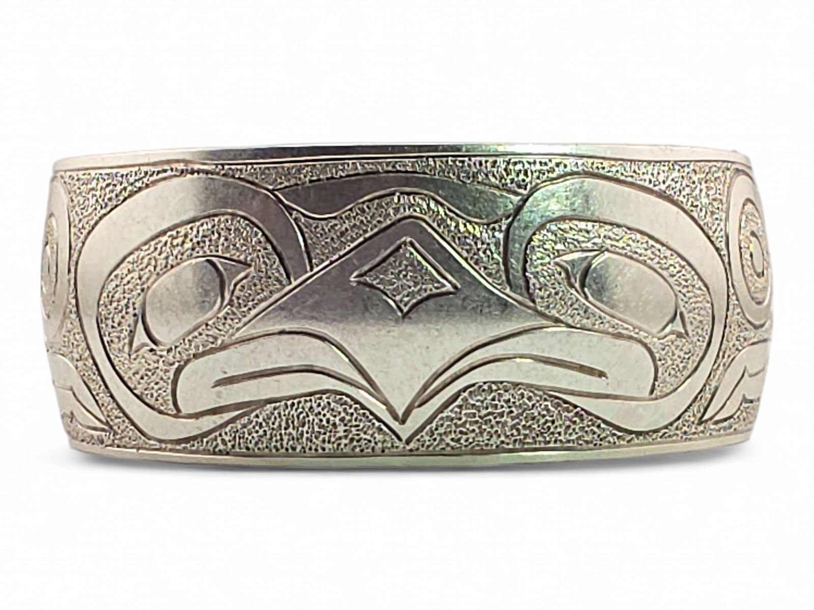 Northwest Coast Sterling Silver Formline Cuff Bracelet: A handcrafted sterling silver cuff bracelet with a traditional incised formline eagle design with a hammered background, inscribed Magna N. Carteeti of Anchorage, Alaska, and "Mom", along with a date