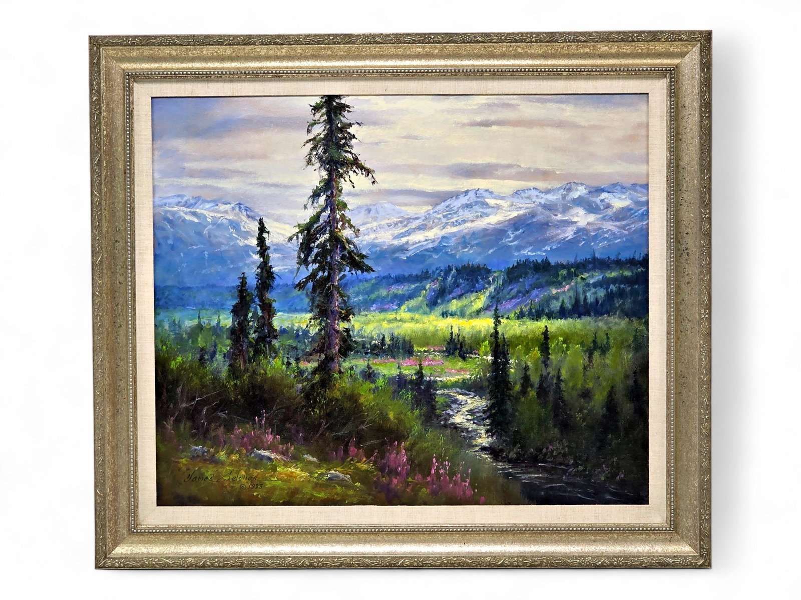 James Belcher Oil Painting of Sunlit Alaska Mountain Valley: An original oil painting by Alaska artist James Belcher (20th/21st century), depicting a radiant summer landscape with a winding stream flowing through a lush valley framed by towering spruce and a di