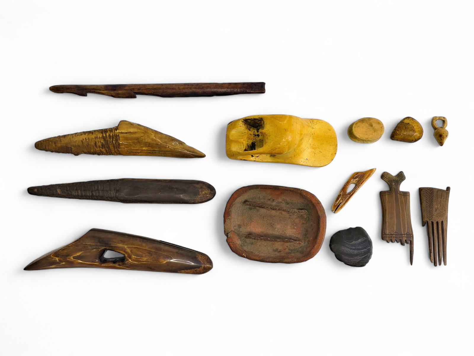Collection of Alaska Native Artifacts with Harpoon Heads & Oil Lamp: A collection of thirteen Alaska Native artifact implements and ornaments crafted primarily from fossil walrus tusk and associated materials, illustrating both hunting technology and domestic life in t