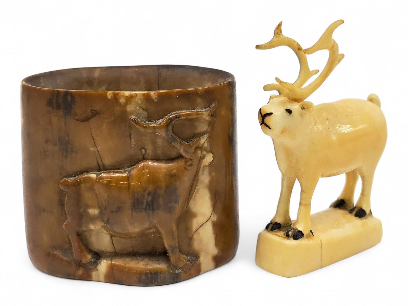 Early Eskimo Fossil Walrus Tusk Caribou Vessel & Carving: Two early 20th-century Eskimo carvings crafted from walrus tusk, both featuring the relatively uncommon subject of the caribou. The first is an open-topped vessel, likely intended as a toothpick holde