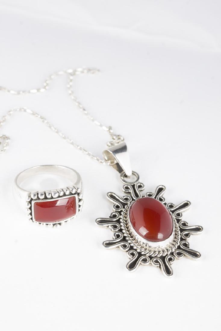 Sterling Carnelian Ring & Pendant on Silver Chain: Sterling and carnelian ring. Carnelian is 13mm x 8mm and surrounded by sterling beads. SIze 8. 7.8gms. Sterling and carnelian pendant in a modified sunburst design. Carnelian is 17mm x 9mm. Pendant is