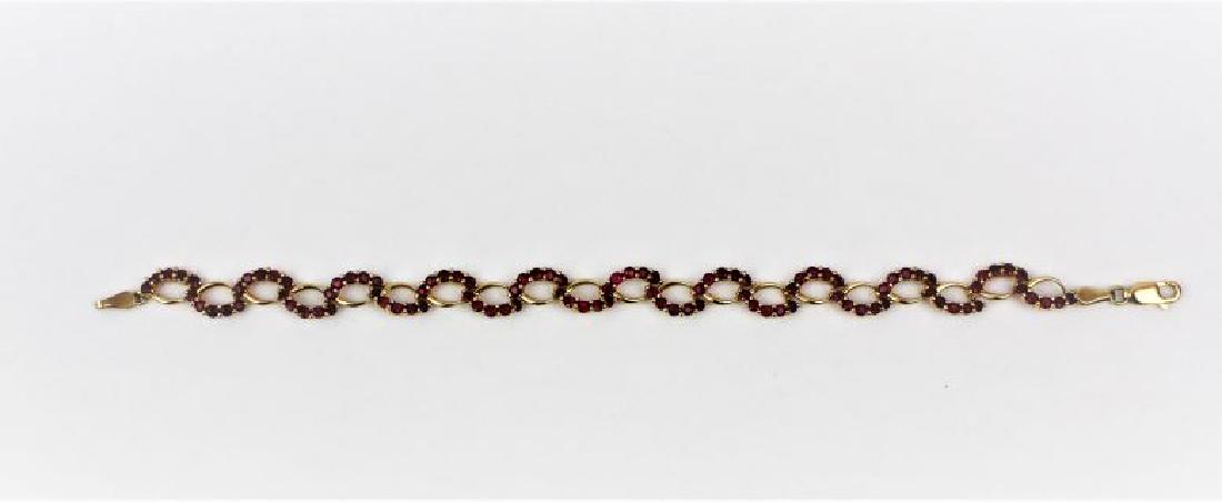 Ruby Link Bracelet 10KT Yellow Gold: 20 Link Ruby bracelet 5 rubies per link, 1mm rubies. 7.25in length. Rubies alternate side to side with 10KT on this unique oval design link bracelet. Lobster clasp. 7.2g.