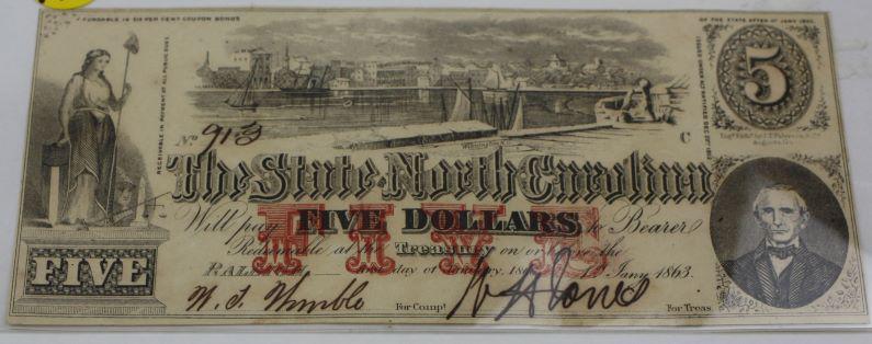 1863 State of N. Carolina $5 Note: 1863 State of North Carolina $5 note. Liberty and the Port of Wilmington NC are represented. Note is clean with good edges, no folds or pinholes. Comes with protective sleeve.