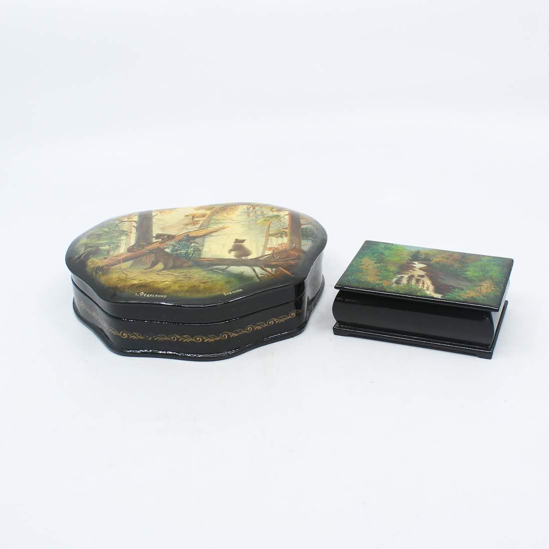 Russian Hand-Painted and Lacquered Wooden Boxes: A pair of Russian hand-painted and lacquered wooden boxes. One box features a scene of Cullasaja Falls in North Carolina and the other features a scene of a mother bear and her three cubs climbing on 