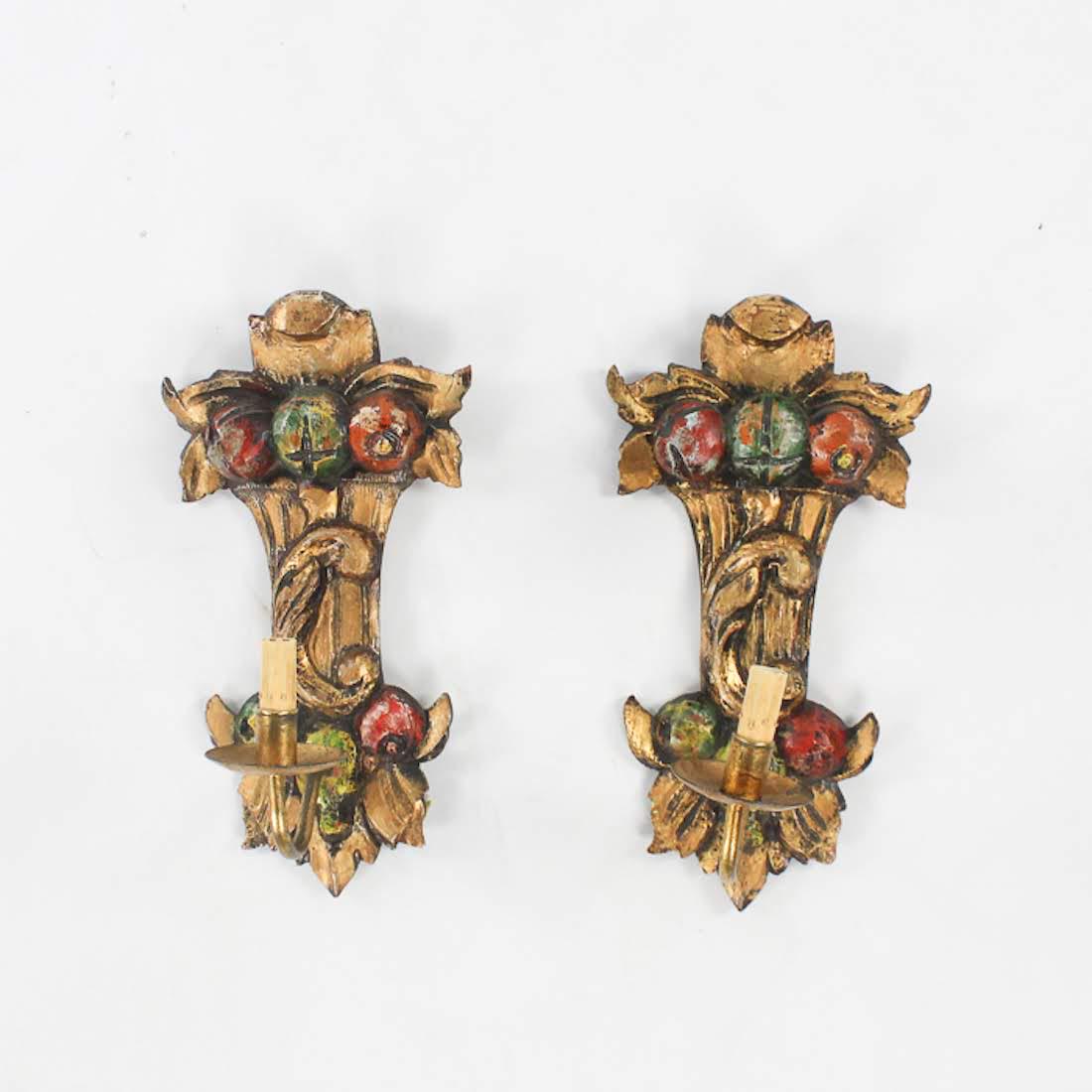 Pair of Antique Italian Hand Painted Wooden Sconces: A pair of antique Italian hand-painted wooden sconces. These sconces features a fruit and foliate motif in a palette of gold, red, and green. They are unmarked. Dimensions: 17 x 8.5 x 8 (for one) Flat