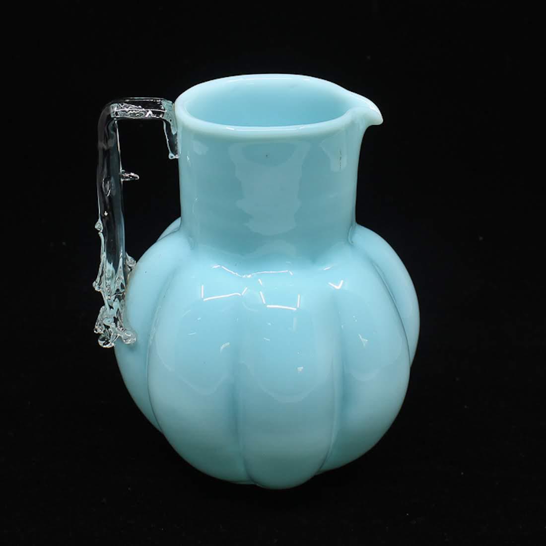 Hand-Blown Turquoise Glass Pitcher: A hand-blown turquoise glass pitcher. This piece features melon ribs throughout the body and a clear hand with a drip effect. It is unmarked. Dimensions: 6 x 6 x 5 Flat Rate Shipping (not calculated):