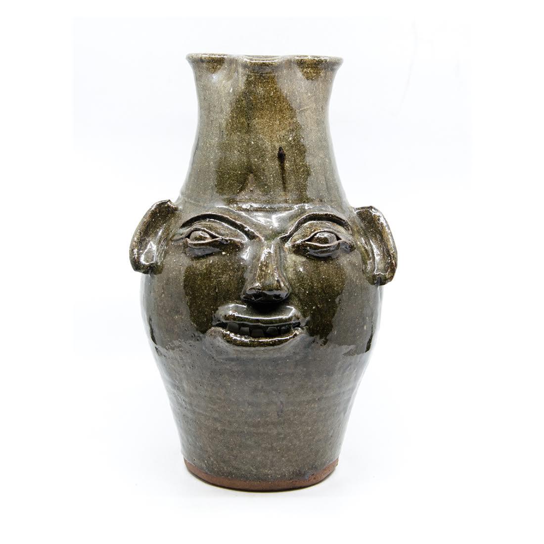 Charles Lisk Folk Art Alkaline-Glazed Pottery Face Jug: A vintage folk art alkaline-glazed stoneware pottery face jug attributed to Charles Lisk. This piece features a textured brown glaze throughout and applied facial features. It is marked Vale, NC and s