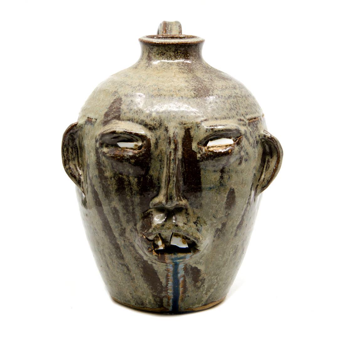 W.A. Flowers Signed Folk Art Pottery Face Jug c. 1987: A 1987 folk art alkaline-glazed stoneware pottery face jug by William Allen Flowers. This piece features a beige and brown streaked glaze throughout and applied facial features. It is signed and dated