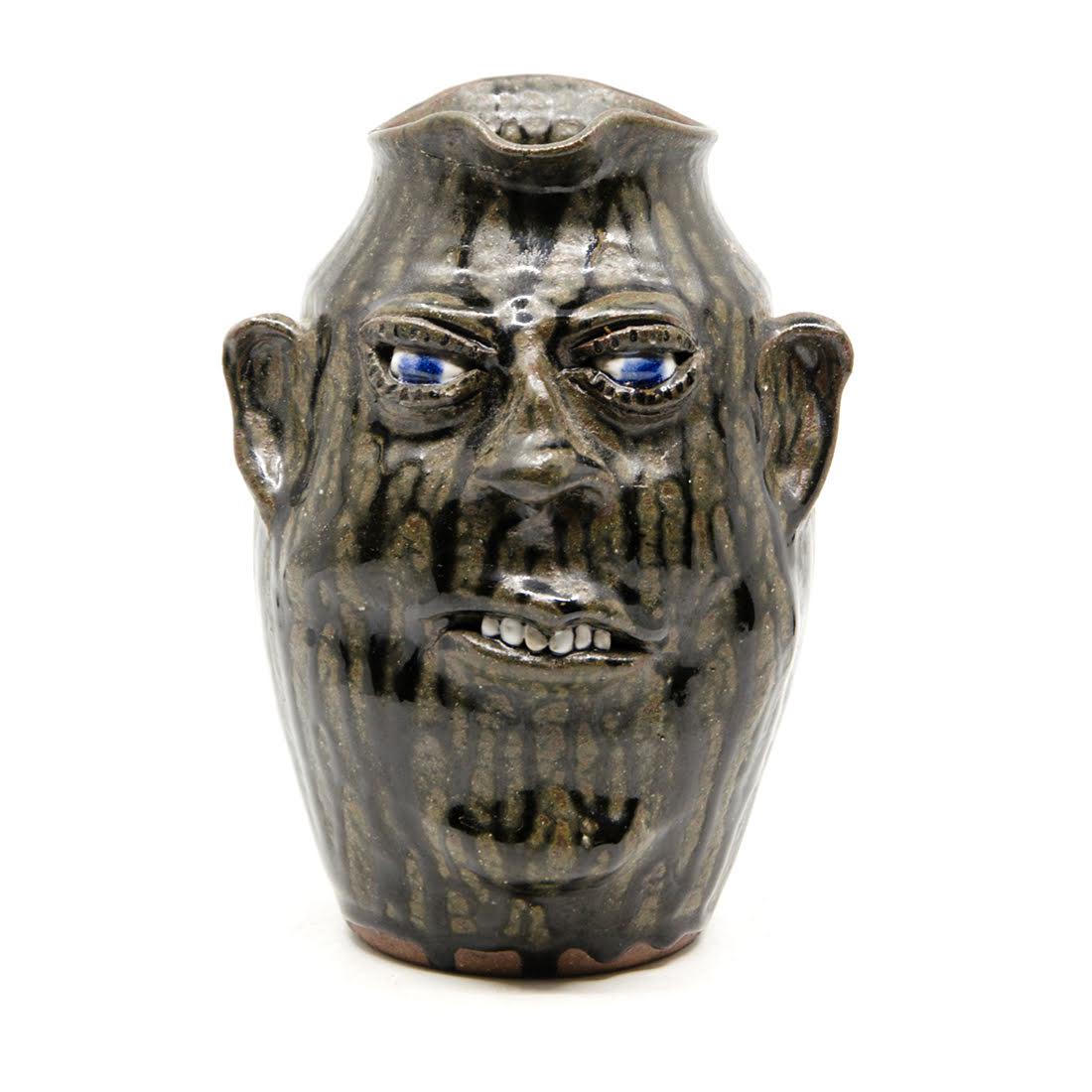 Meaders Signed Folk Art Pottery Face Jug c. 1989: A 1989 folk art alkaline-glazed stoneware pottery face jug by Cleater and Bill Meaders. This piece features a multi-tonal brown drip glaze throughout and applied facial features. It is signed and date