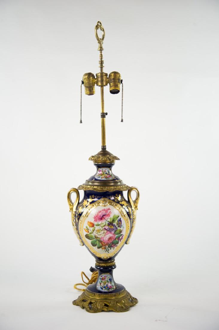 Sèvres Cobalt Blue Urn Converted Lamp: A French Sèvres having ormolu bronze base and leaf handles bronze trim porcelain lid with bronze top and adjustable height stem with double sockets and loop finial with pull chains. Sides each have f