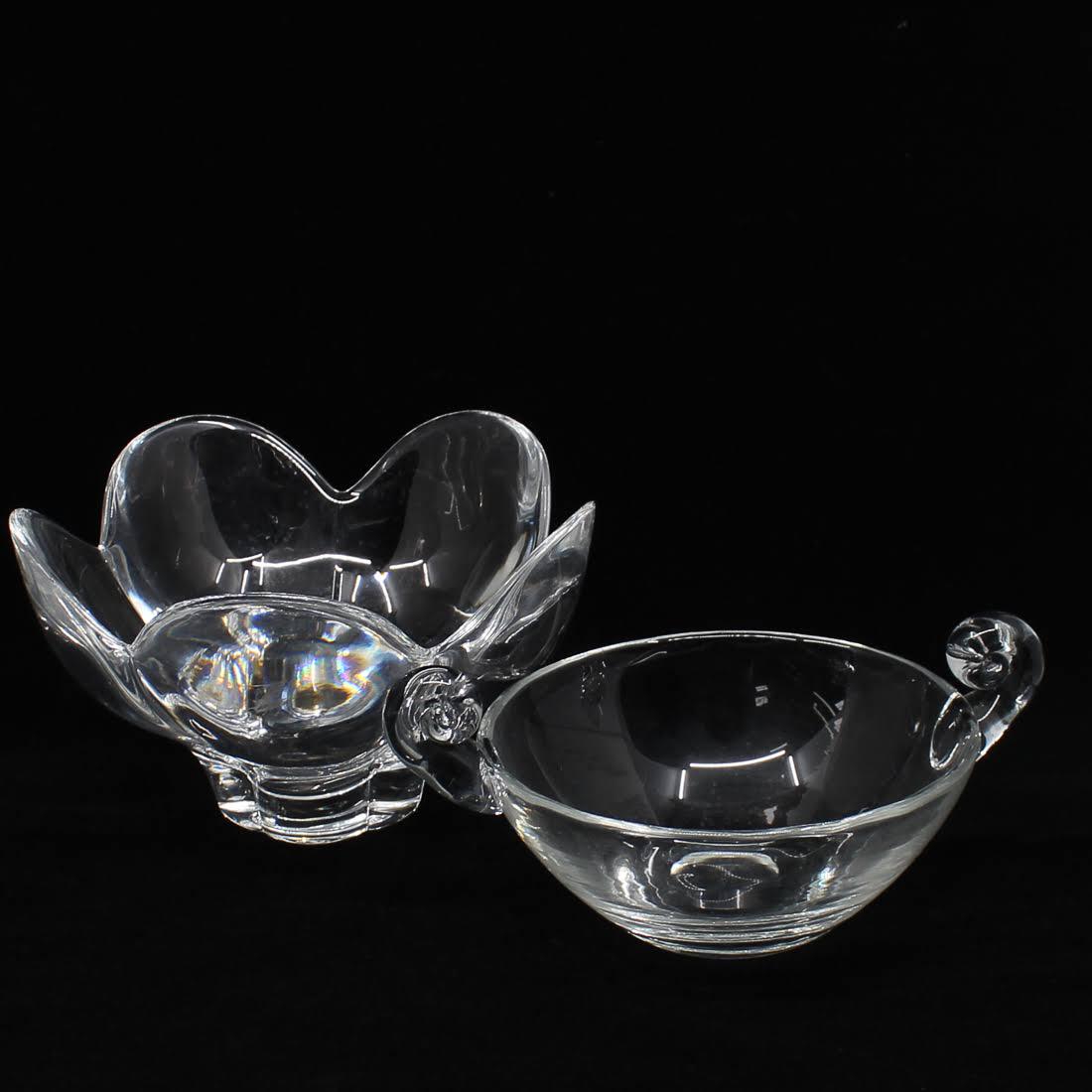Crystal Bowls Including Signed Orrefors: A grouping of two crystal bowls. This lot includes a signed Orrefors bowl, which takes the form of a flower, and an unmarked bowl with scroll handles. Dimensions: 5 x 7.75 x 7.75 (for largest) Flat Ra
