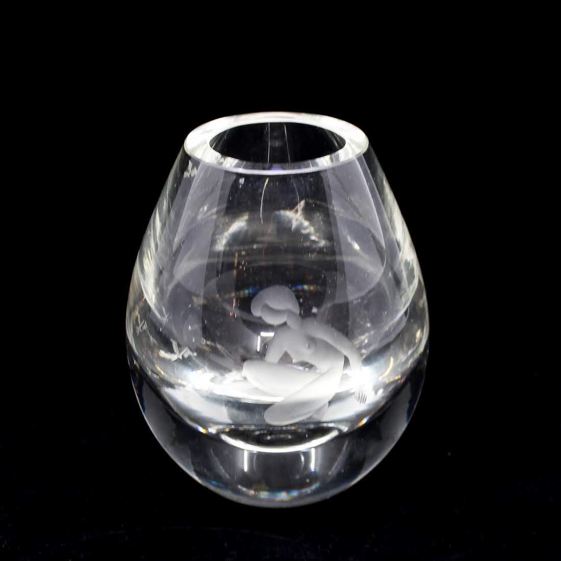 Holmegaard Signed Etched Glass Vase c. 1956: A vintage Holmegaard glass vase circa 1956. This piece features an etched design of a nude woman crouched down with her arm outreached towards a bird. It is signed and dated on the underside. Dimensio