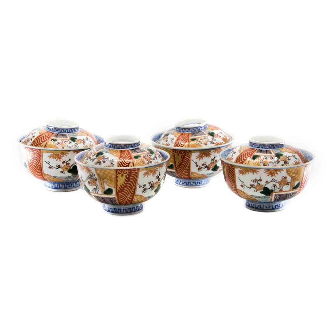 Set of Four Antique Imari Lidded Porcelain Rice Bowls: A set of four antique Imari lidded porcelain rice bowls. The exterior of each bowl features a three-section design depicting a garden scene in each section. The interior of each is decorated with a bl