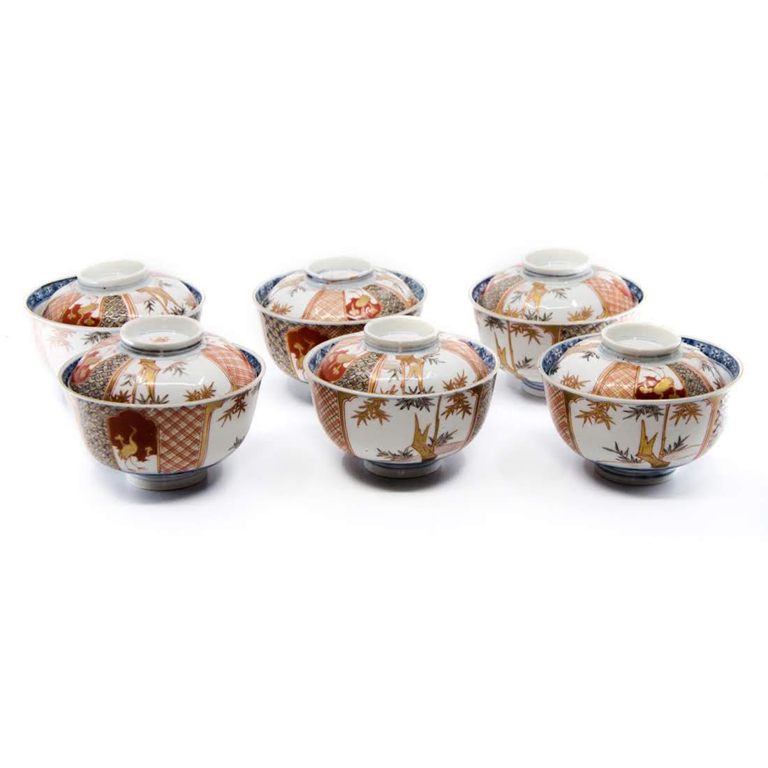 Set of Six Antique Imari Lidded Porcelain Rice Bowls: A set of six antique Imari lidded porcelain rice bowls. The exterior of each bowl features a four-section design with two sections depicting bamboo stalks and the other two depicting a crane. The inte