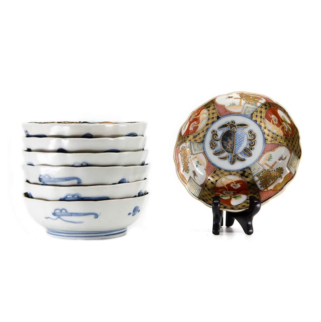 Set of Seven Antique Imari Porcelain Bowls: A set of seven antique Imari porcelain scalloped rim bowls. The interior of each bowl features a six-section design with three sections depicting a garden scene and the other three depicting trees. In