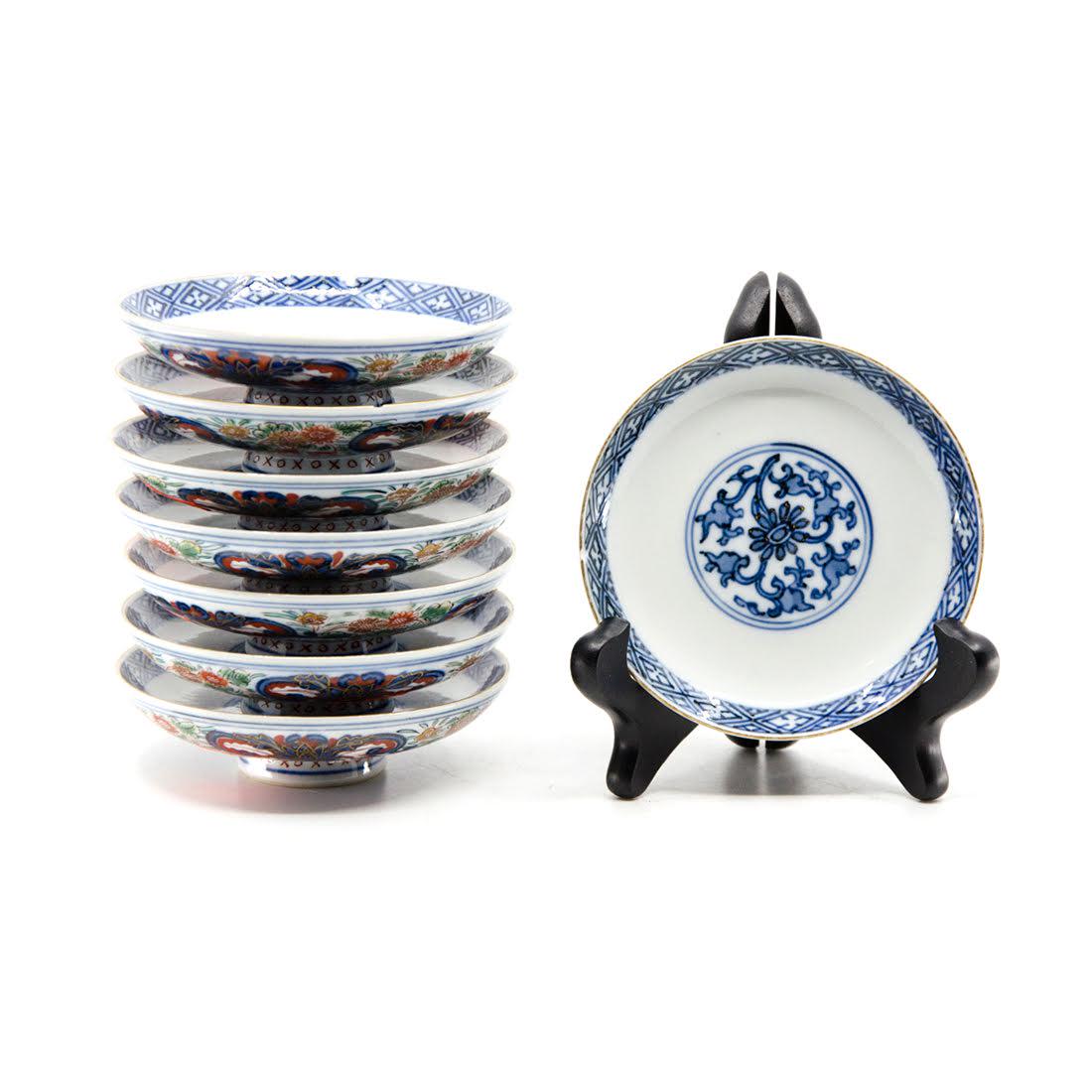 Set of Eight Antique Imari Footed Porcelain Dishes: A set of eight antique Imari porcelain footed dishes. The exterior of each bowl features an ornate floral design in a multi-colored palette. The interior of each is decorated with a blue and white flo