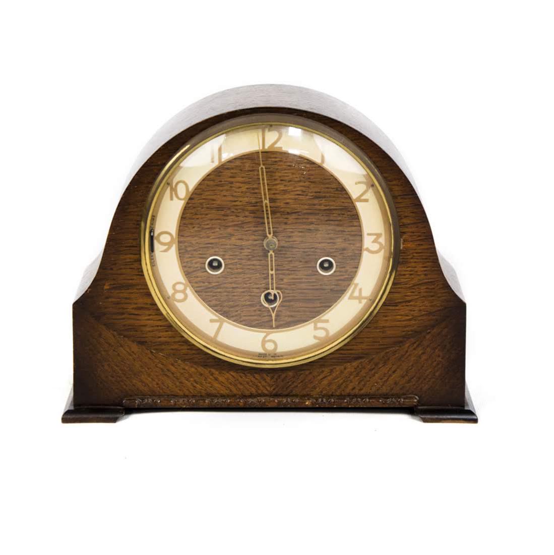 Art Deco Wooden Mantle Clock by Smiths of Great Britain: An antique Art Deco wooden mantle clock by Smiths of Great Britain. This piece features a geometric form with a rounded top edge. The key is included. Dimensions: 9"H x 11"W x 4.5"D Flat Rate Shipping