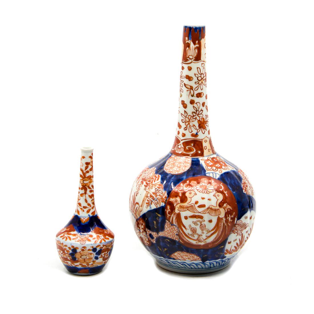 Antique Imari Hand-Painted Porcelain Vases: A grouping of two antique Imari hand-painted porcelain vases. The larger piece features a floral, foliate, bird, and fan design in a palette of blue and red. The smaller features a floral and foliate 